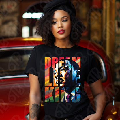 Woman wearing a black t-shirt with a colorful graphic design in front of a red car.