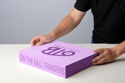 Person holding a purple box filled with dtf transfers with 'OTB' 'On the Ball transfers' branding on a gray background