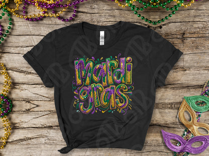 Black t-shirt with 'Mardi Gras' text in colorful letters on a wooden surface with Mardi Gras decorations.