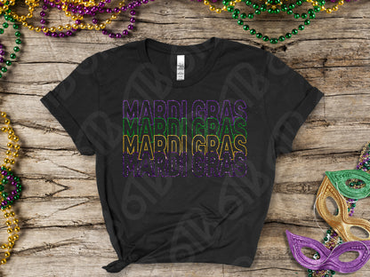 Black t-shirt with 'MARDI GRAS' text in purple, gold, and green on a wooden surface with Mardi Gras beads and a mask.
