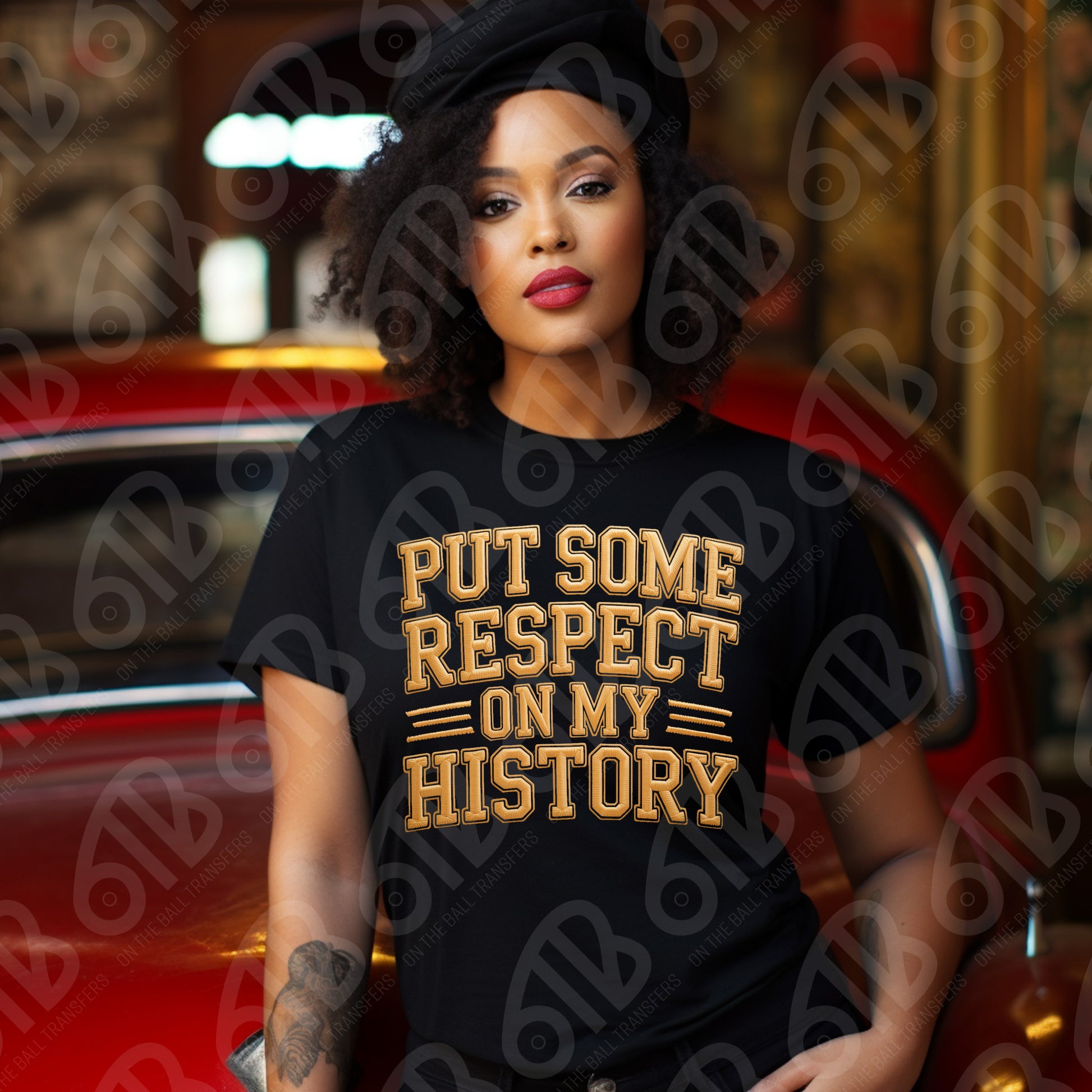 Woman wearing a black t-shirt with gold text 'PUT SOME RESPECT ON MY HISTORY' in front of a red car.